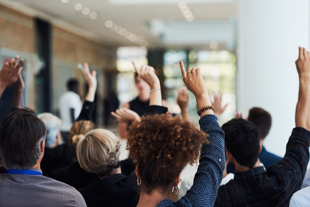 Audience members raise their hands to ask questions